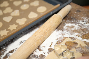 Homemade cookie baking process with dough, rolling pin and cutters. Step by step preparation of festive cookies on wooden table, cozy home kitchen, family baking concept.
