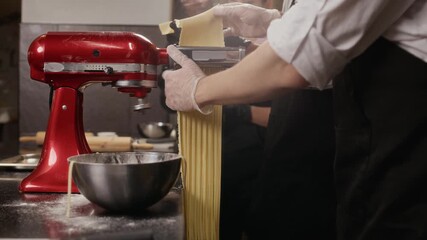 Side view of unrecognizable male chef using noodle cutter making artisanal pasta during group culinary class in restaurant kitchen