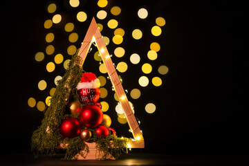 Modern DIY wooden Christmas tree with LED lights, moss, red balls and ornaments on a neutral background