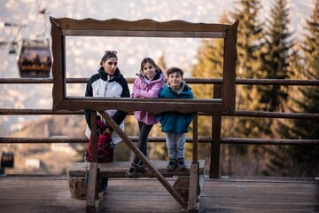 Family posing in wooden frame on mountain in autumn