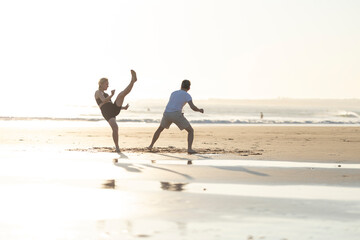 People practicing capoeira martial art on beach