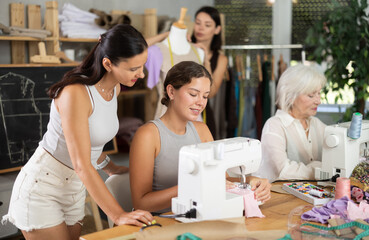 Group of women of different ages sew and work with mannequin during sewing master class
