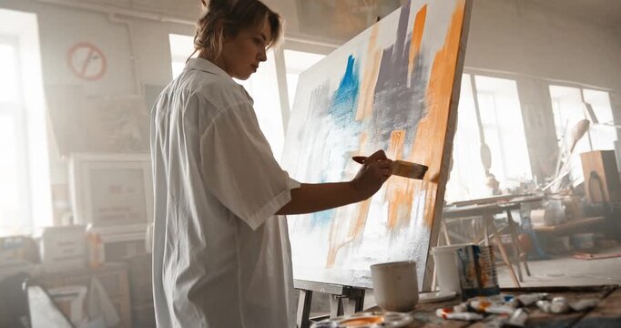 Inspired female artist painting abstract masterpiece on canvas