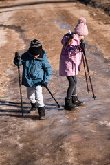 Children hiking on icy trail with trekking poles