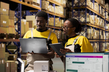 African american employees working on order processing with devices, fulfillment center ensures efficient workflow. Managing parcels data for express delivery. Online shopping logistics.