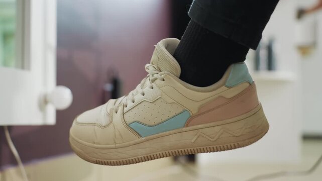 casual footwear serenity, calm ambiance captured with beige sneakers and subtle lighting effects, tranquil snapshot showcasing light beige sneaker hanging by window during restful pause