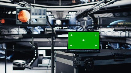 Fototapeta premium Green screen laptop in spacecraft used for data input next to nearby monitor showing Mars mission analysis. Mockup notebook assisting space station crew in managing planetary observations