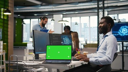 Technician next to office coworkers developing software applications using green screen laptop, integrating AI automation. IT expert debugging applications with mockup notebook, camera A