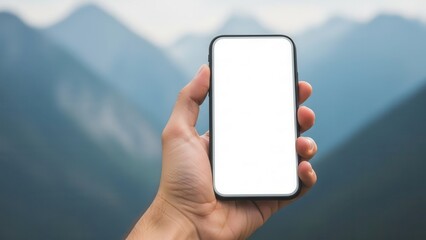 Hand holding smartphone with empty white screen in front of blurred mountains