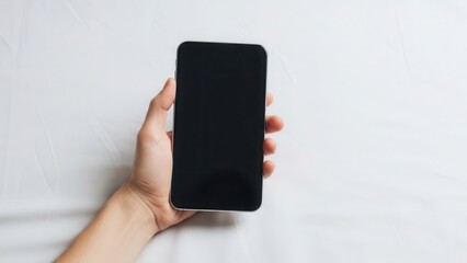 Minimalist composition with a hand holding a blank screen device on a white sheet