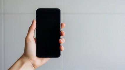 Minimalist hand holding smartphone with blank screen against neutral wall background