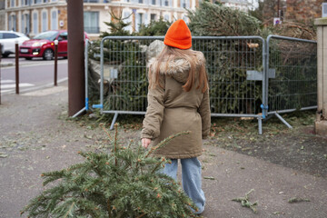 The girl is throwing out the Christmas trees behind the fence