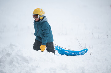 Child pulling a sled in deep winter snow