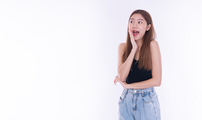 Surprised young Asian woman looking at empty copy space with hand on cheek on white background. Shocked beautiful female model showing product advertisement concept with open mouth.