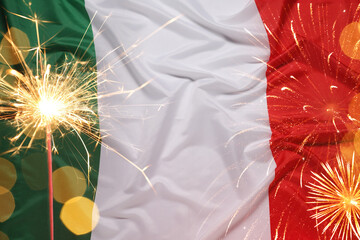 Flag of Italy, burning sparkler, fireworks and bokeh lights. National holiday