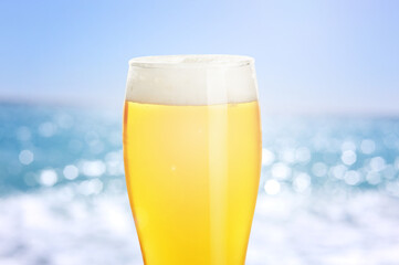 Glass of beer near sea, closeup. Refreshing summer drink