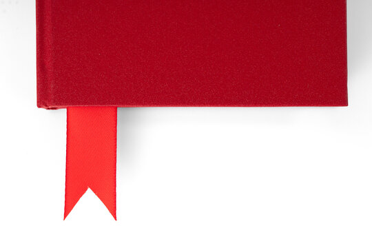A red notebook with a textured red cover and a red ribbon bookmark extending from between the pages