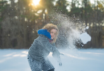 Amazed kid enjoying winter play with snowball. Happy child throwing snow outdoors. Winter outdoor...