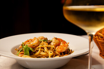 Shrimp pasta and glass of white wine close up.