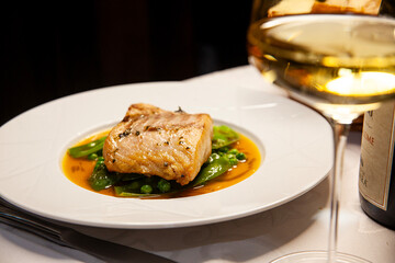 fish and peas dish close up and glass of white wine