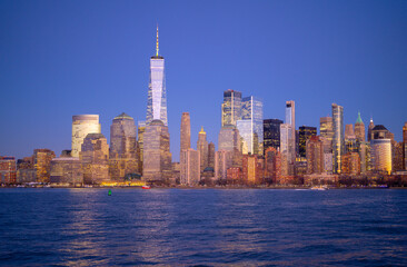 Obraz premium Manhattan skyline glowing at dusk. NYC skyline with downtown towers. New York City skyline as a travel destination. Manhattan skyscrapers forming the city horizon. NYC skyline panorama.