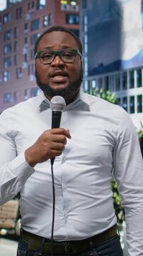 Vertical Video Adult male correspondent conducting public interview on city street, using confident dialogue to share news coverage. Demonstrating skill in storytelling in a metropolitan center