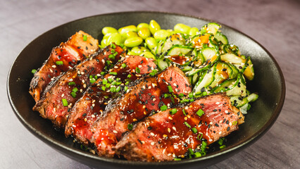Beautiful oriental bowl with thin slices of rare sirloin, edamame, sunomono salad, and teriyaki...
