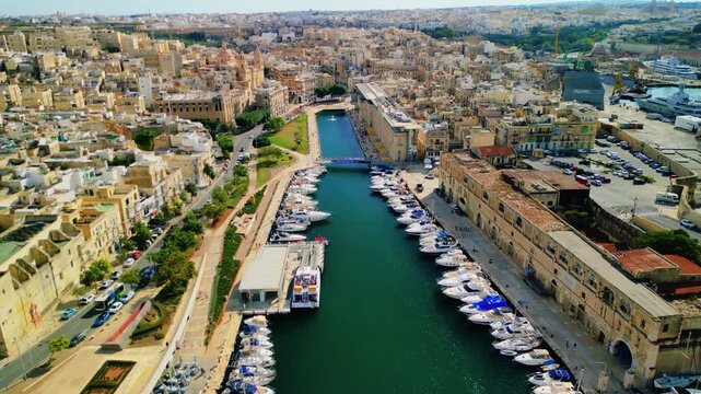 Aerial 4K flyover of Dockyard Creek marina towards the Church of the Immaculate Conception in Bormla, Malta
