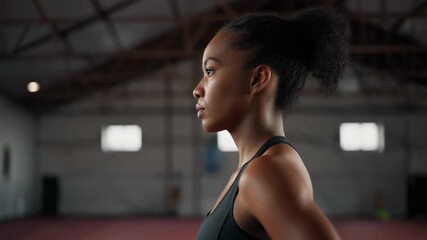 Close up profile of a focused and determined young African American woman in athletic wear, standing confidently in a gym, embodying strength and dedication to fitness training - Powered by Adobe