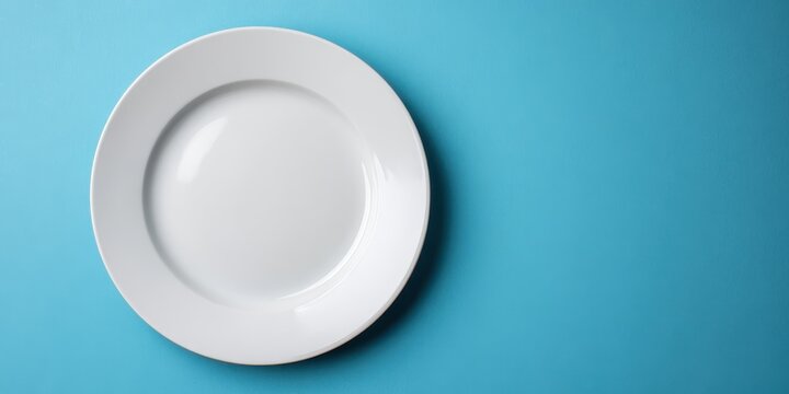 Vibrant photo of Empty white ceramic plate on a solid blue background, top view with copy space