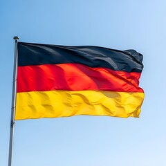 Naklejka premium The Waving Flag of Germany Proudly Displayed Against a Clear Blue Sky