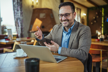 Fototapeta premium Businessman having online video call using laptop in cafe