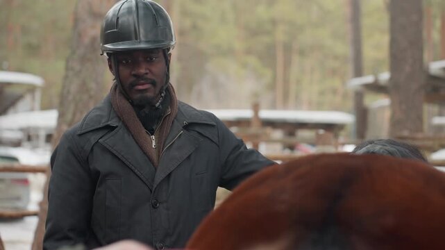 calm guardian overseeing horse grooming, snowy yard scene with attentive caretaker observing, serene observer in layered clothing attentively monitoring equine care in snowy stable area