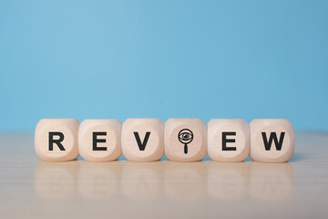 Review text on wooden cube blocks. Review evaluation time for review inspection assessment auditing. Business review for learning, improvement, planning and development for the future.