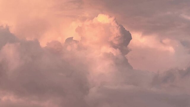 A pinkish cumulus cloud moves against a background of other pink clouds at dawn. Speeding up by a factor of 1.5. Majorca, Spain.