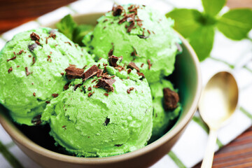 Tasty mint chocolate chip ice cream, spoon and towel on wooden table, closeup
