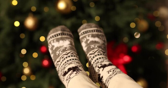 Woman wearing cozy socks against twinkling Christmas lights, closeup