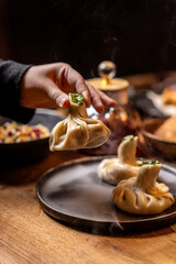 Hand Lifting Steaming Georgian Khinkali Dumpling At Restaurant