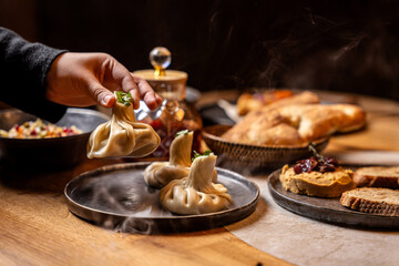 Hand Lifting Steaming Georgian Khinkali Dumpling In Restaurant