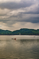 Rowo Jombor Lake, Klaten Regency, fishermen on a raft in the middle of the lake with a backdrop of mountains and cloudy skies