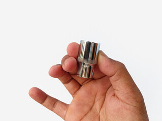 Authentic close up of a human hand holding a chrome socket head, isolated on a white background, showing real size, grip, and everyday mechanical workshop use.