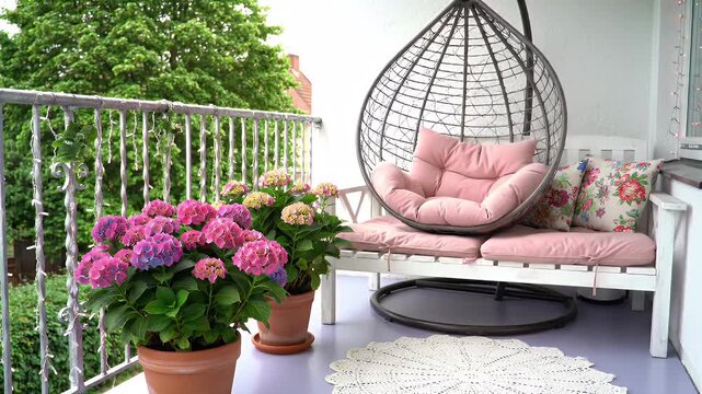 Charming Outdoor Balcony Lounge with Pink Cushions and Hanging Wicker Chair Amid Greenery