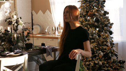 A cute girl in black sits at a set Christmas table