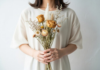清楚な装いの女性が持つ、可憐なドライフラワーのブーケ