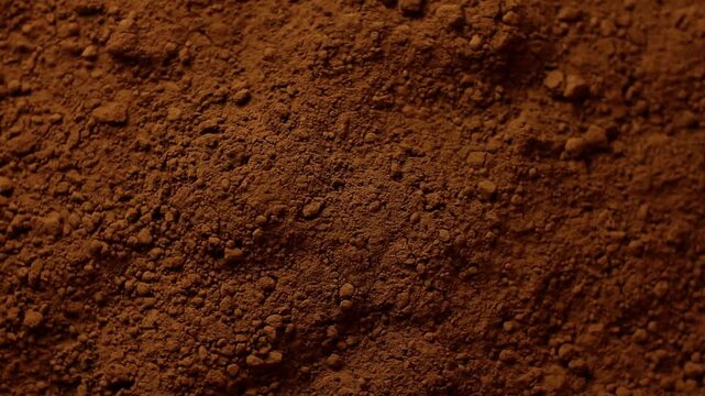 Surface of cocoa powder shown in close-up, with fine particles and irregular distribution.