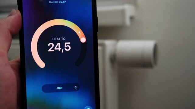 Male hand increasing thermostat temperature with data shown in mobile application.