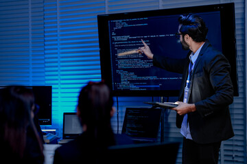 Fototapeta premium A focused male AI solutions architect in a futuristic control hub debates generative AI applications collaborating on a complex machine learning model with his team under atmospheric blue lighting.