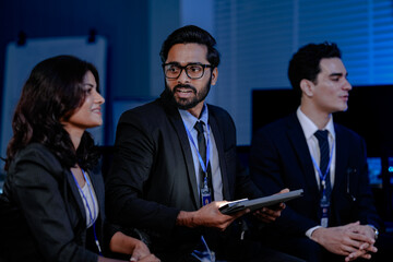 A crisis management team discusses an urgent data security threat. Diverse experts review a rapid response plan to protect customer data and ensure business continuity.