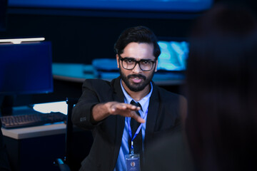 A diverse tech team discusses a new digital strategy. An Indian manager uses a tablet to show AI driven analytics for sustainable ESG growth to a colleague.