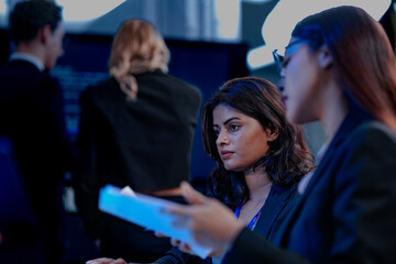 Intense collaboration hub. Diverse AI team deep dive into project data late night. Manager guides Asian colleagues reviewing analytics for a new service launch in tech office.